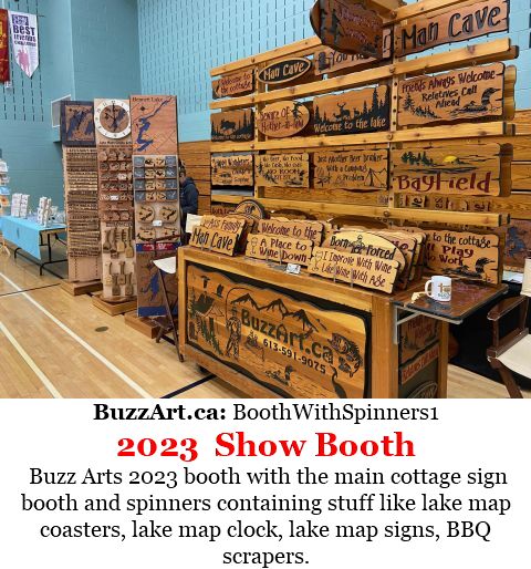 Buzz Arts 2023 booth with the main cottage sign booth and spinners containing stuff like lake map coasters, lake map clock, lake map signs, BBQ scrapers.